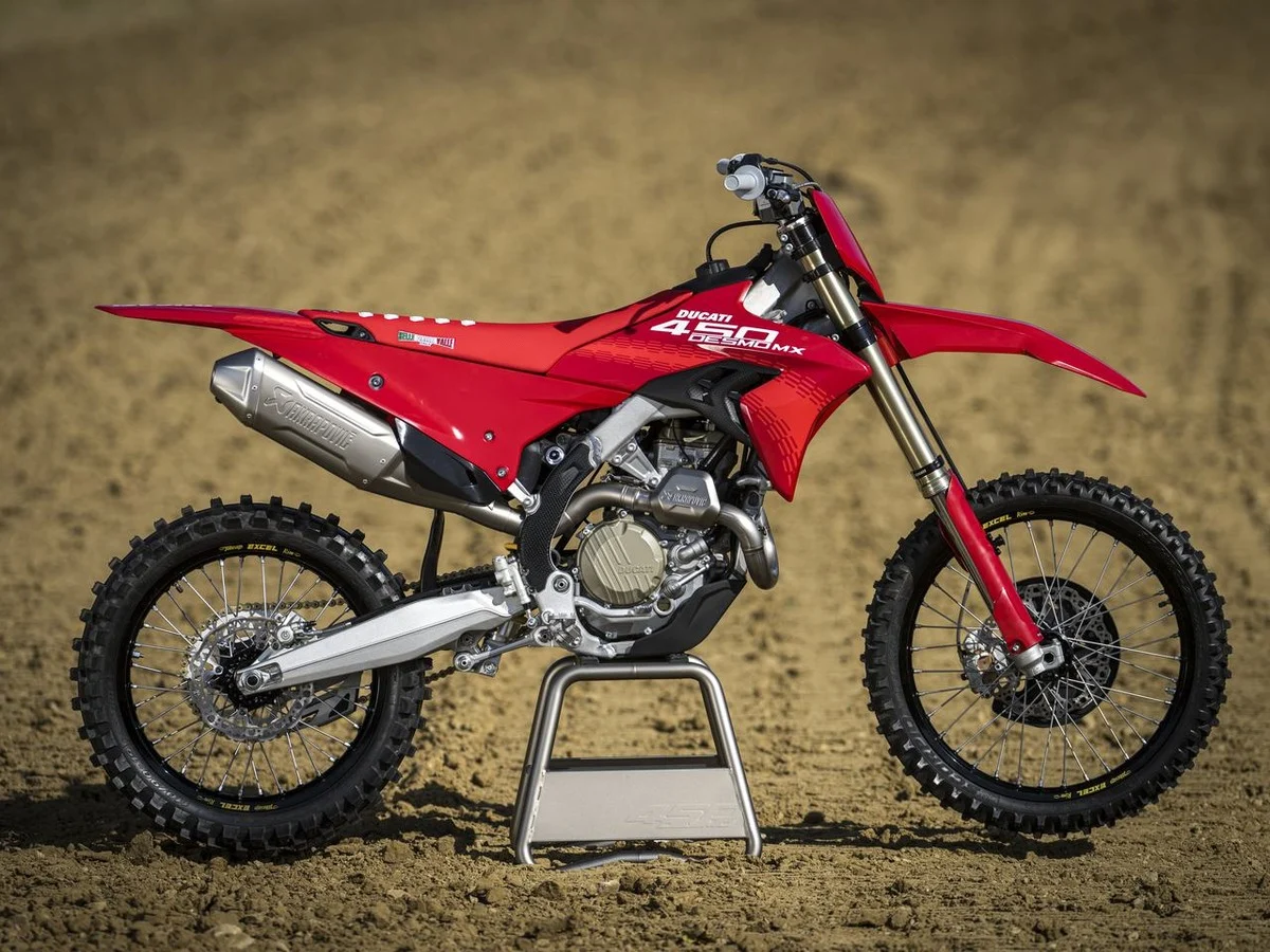 Ducati Desmo450 MX cruzando pista de motocross sob céu azul
